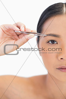 Half face of natural woman using tweezers