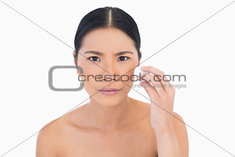 Frowning beautiful model using cotton pad on her face