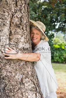 Retired woman hugging a tree and smiling