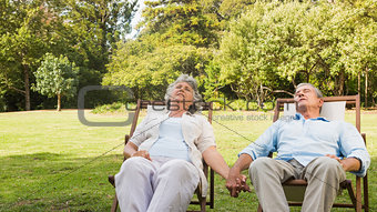 Mature couple relaxing on sun loungers
