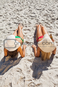 Attractive blonde and brunette in bikinis having beer