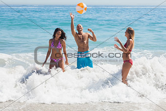 Happy friends playing with a beachball in the sea