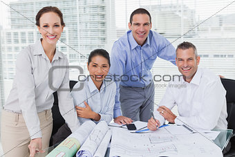 Cheerful architects posing while anaylzing plans together
