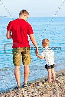 Father and son admiring the sea at sunset