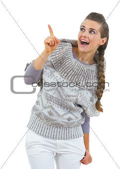 Surprised young woman in sweater pointing on copy space