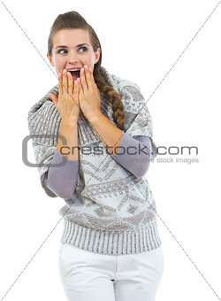 Surprised young woman in sweater looking on copy space
