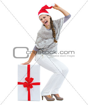 Happy young woman in sweater and christmas hat sitting on big ch
