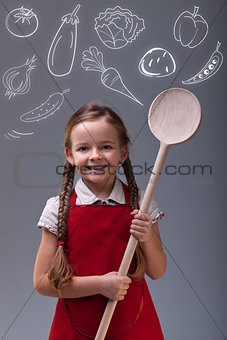 Young girl with apron and large wooden spoon