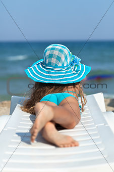 Little girl on the beach relaxing on a deck chair