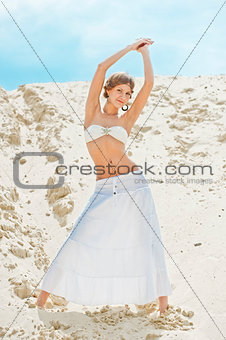 beautiful girl in a white skirt posing on a sand dune
