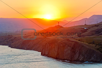 Steep cliff at the edge of the sea at sunset, on the background of the Crimean mountains