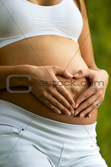 Pregnant woman shaping a heart with her hands.