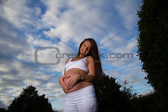 Pregnant woman standing holding belly 