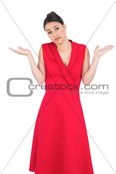 Hesitant elegant brunette in red dress posing