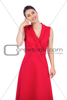 Glamorous model in red dress making phone call gesture