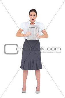 Shocked stylish businesswoman holding newspaper