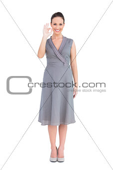 Elegant brunette in classy dress making an okay gesture