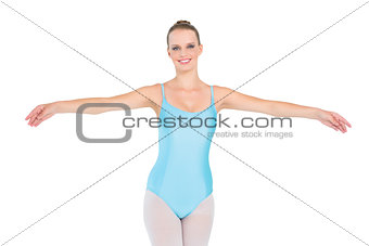 Cheerful pretty ballerina posing raising her arms