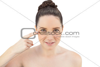 Natural model applying cream on her crows feet