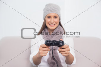 Cheerful brunette with winter hat on playing video games