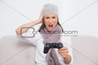 Furious brunette with winter hat on playing video games