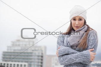 Shivering cute brunette with winter clothes on posing