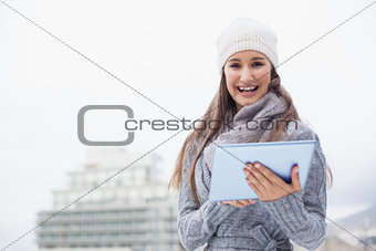 Cheerful woman with winter clothes on using her tablet