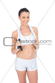 Smiling fit sportswoman holding skipping rope around neck