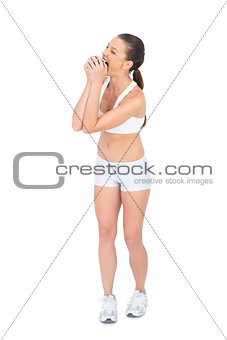 Fit woman in sportswear munching apple