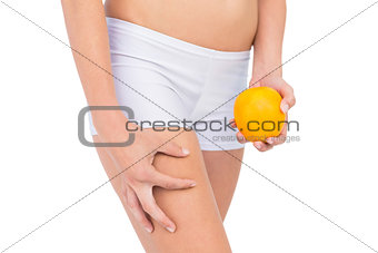 Fit woman in sportswear pressing cellulite on her thigh