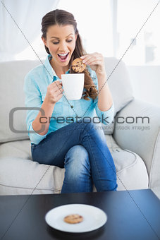 Happy woman dunking biscuit into hot chocolate