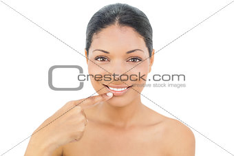 Smiling black haired model pointing at her bottom lip