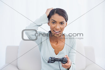 Irritated woman sitting on sofa playing video games