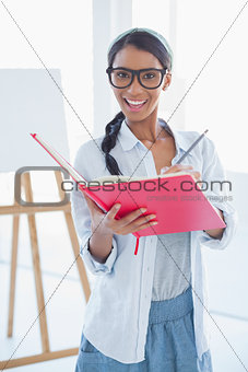 Cheerful attractive artist writing on her notebook