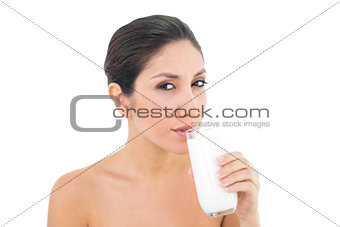 Smiling brunette sipping glass of milk and looking at camera