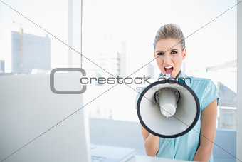 Angry elegant woman shouting in megaphone