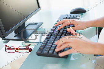 Close up of female hands typing on keyboard at desk