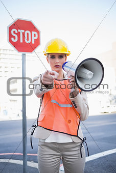 Businesswoman wearing builders clothes pointing at camera