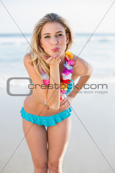 Sexy blonde in bikini wearing hawaii necklace sending an air kiss to camera