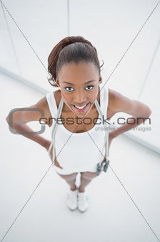 Smiling fit woman holding skipping rope on shoulders