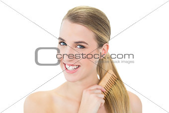 Smiling attractive blonde combing her hair