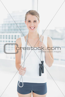 Smiling sporty woman holding skipping rope