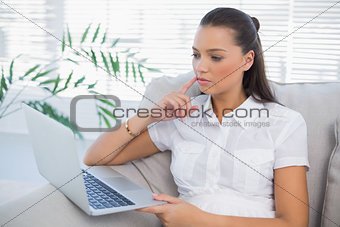 Thoughful woman looking at laptop
