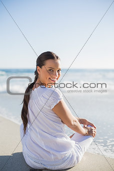 Rear view of smiling woman on the beach looking over shoulder at camera