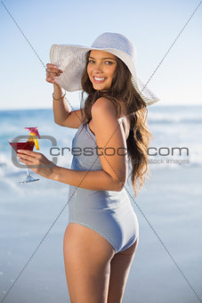 Gorgeous woman in swimsuit holding cocktail looking over shoulder