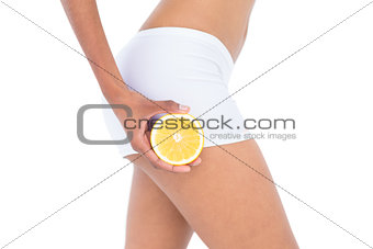 Close up of a fit woman showing half an orange