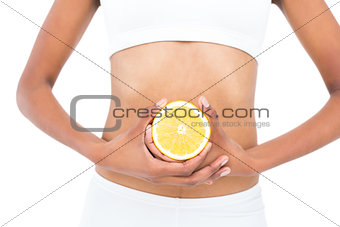 Close up of a fit model keeping half an orange