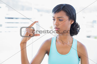 Puzzled black haired woman holding an asthma inhaler