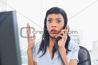 Shocked businesswoman answering the telephone
