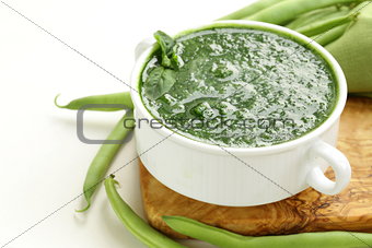 green cream soup of spinach and green peas in white bowl